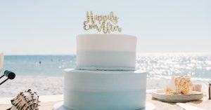 Beautiful beach wedding cake with seashells under a sunny sky, perfect for coastal weddings.